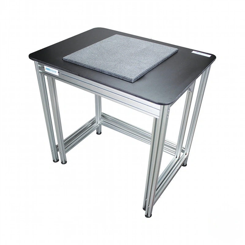 Black desktop with silver metal legs and a gray textured mat on top