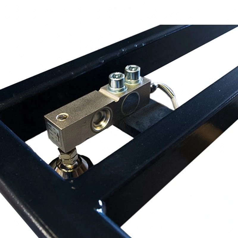 A metallic load cell with a rectangular body, featuring two threaded bolts on top and a circular indentation, mounted within a black metal frame