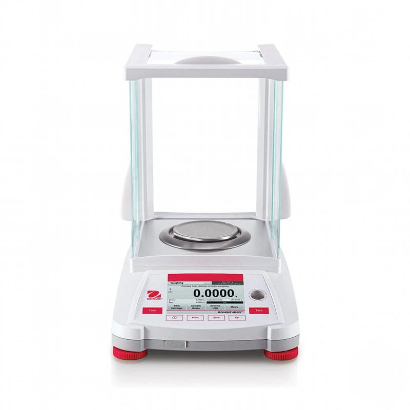 White and red analytical balance with a transparent glass draft shield, digital display showing 0.0000 g, and stainless steel weighing platform