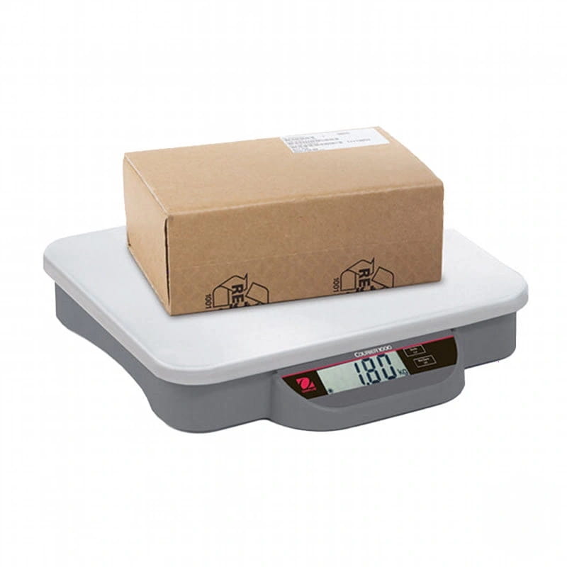 Gray digital scale with a white top surface and a brown cardboard box resting on it
