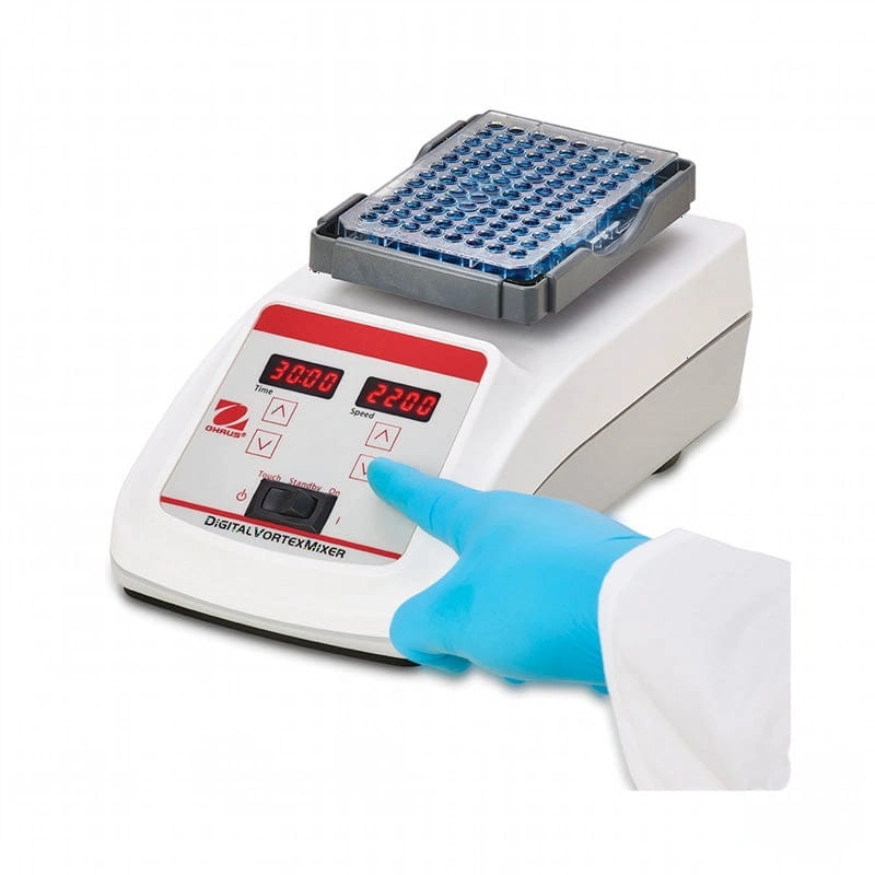 White digital vortex mixer with red display and control panel, featuring a gray tray holding blue microcentrifuge tubes