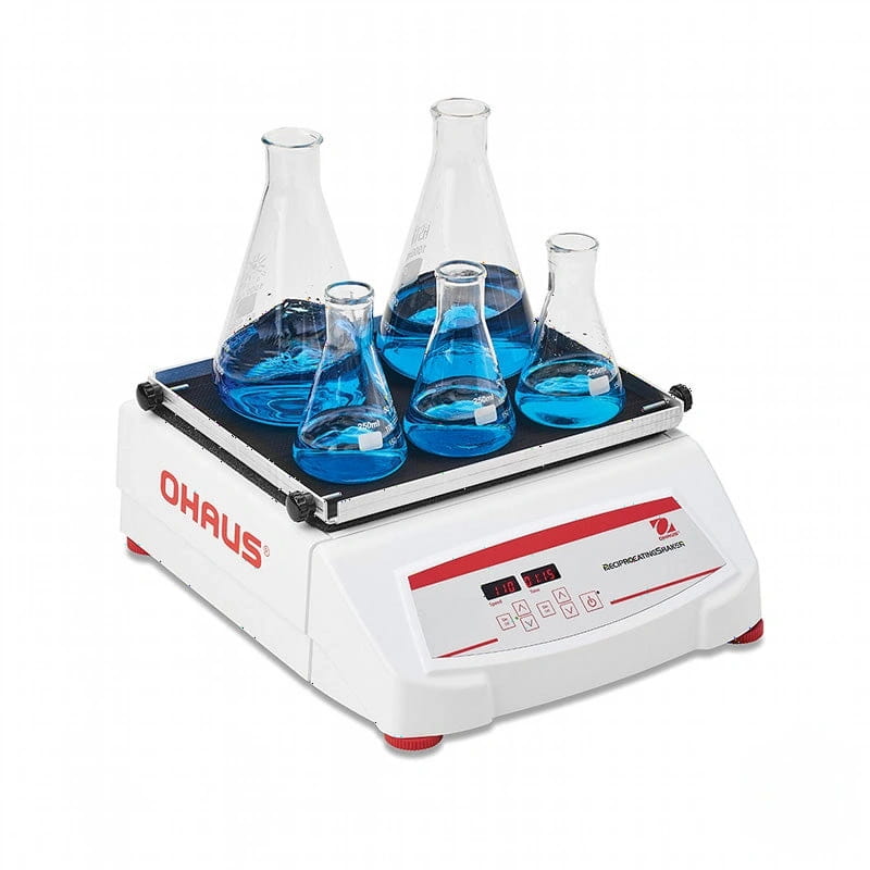 White ohaus laboratory rotator with red accents, holding five clear glass conical flasks filled with blue liquid