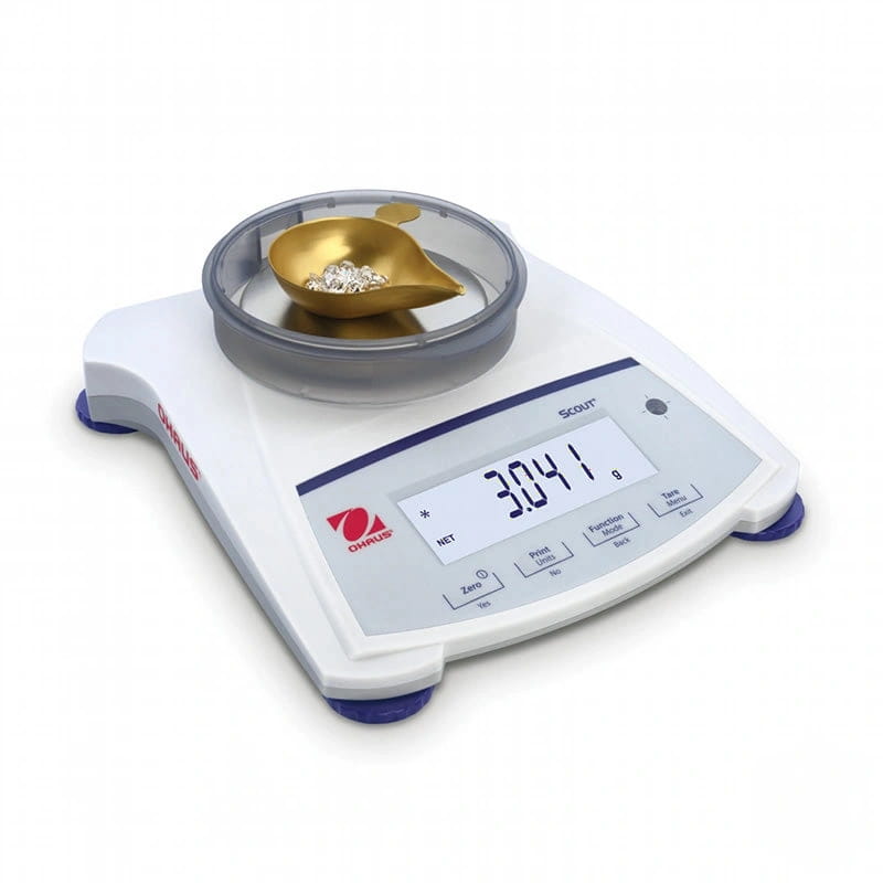 White ohaus scout digital scale with a transparent weighing pan holding a golden leaf-shaped scoop containing small white crystals
