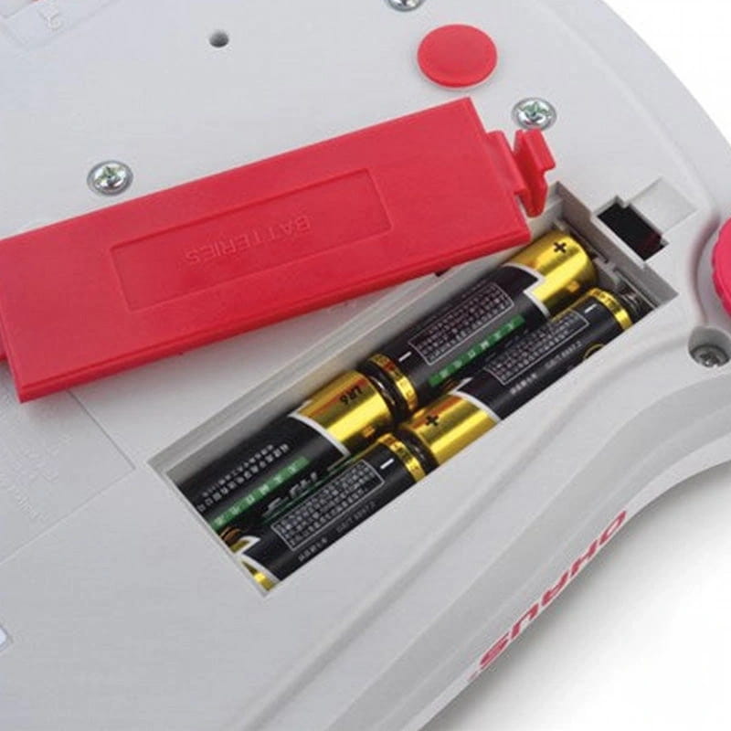 White plastic device with red battery cover and four aa batteries inserted