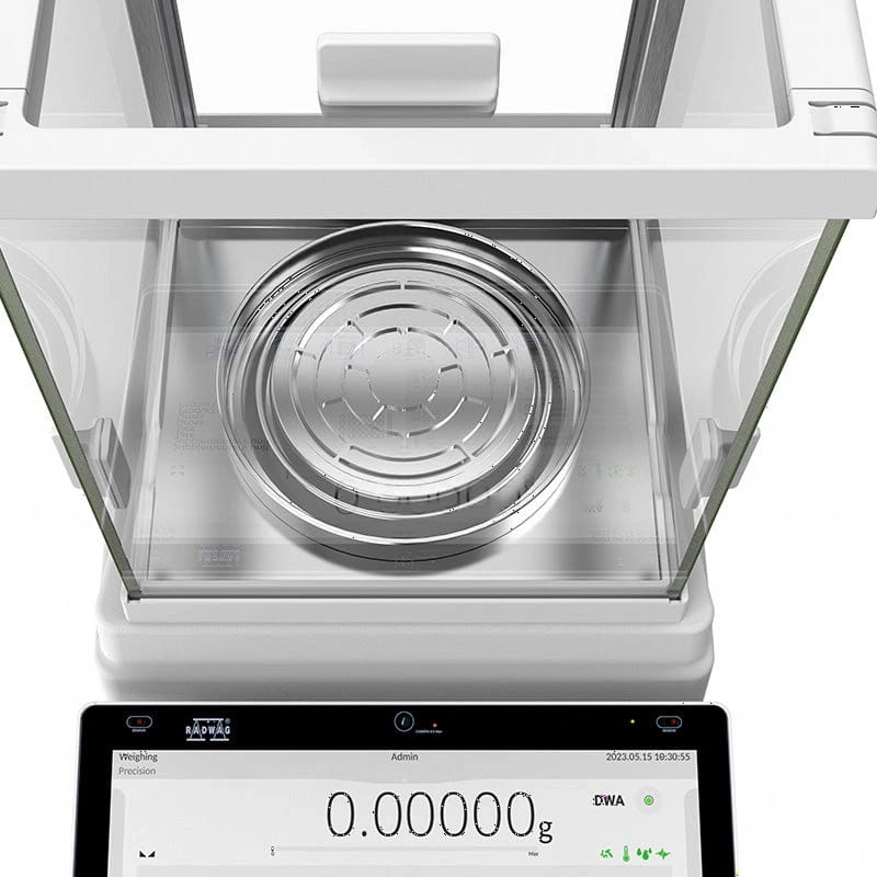 White analytical balance with a stainless steel weighing pan and digital display showing zero grams