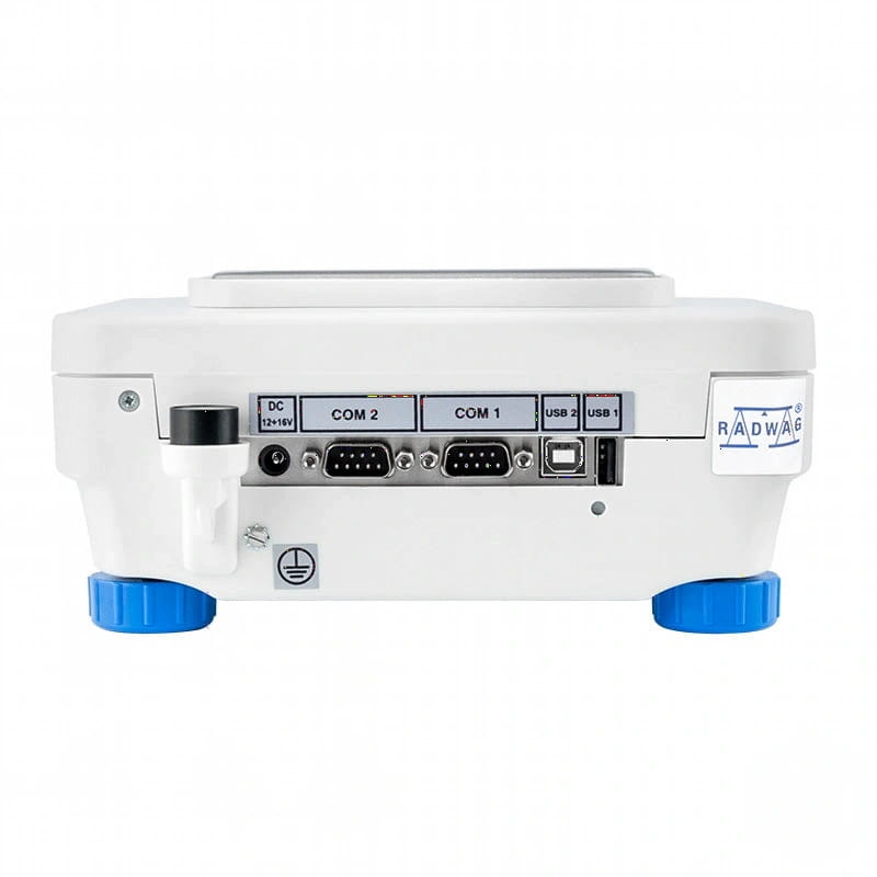 White radwag laboratory balance with blue feet and a panel of labeled ports including dc, com 1/2, usb 1/2